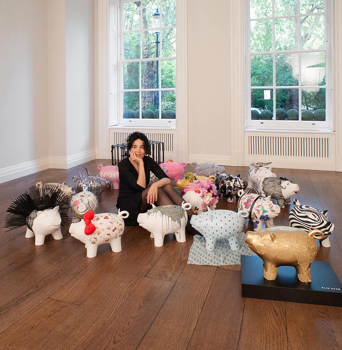 Artist Mouna Rebeiz sits amongst bespoke piggy banks 
