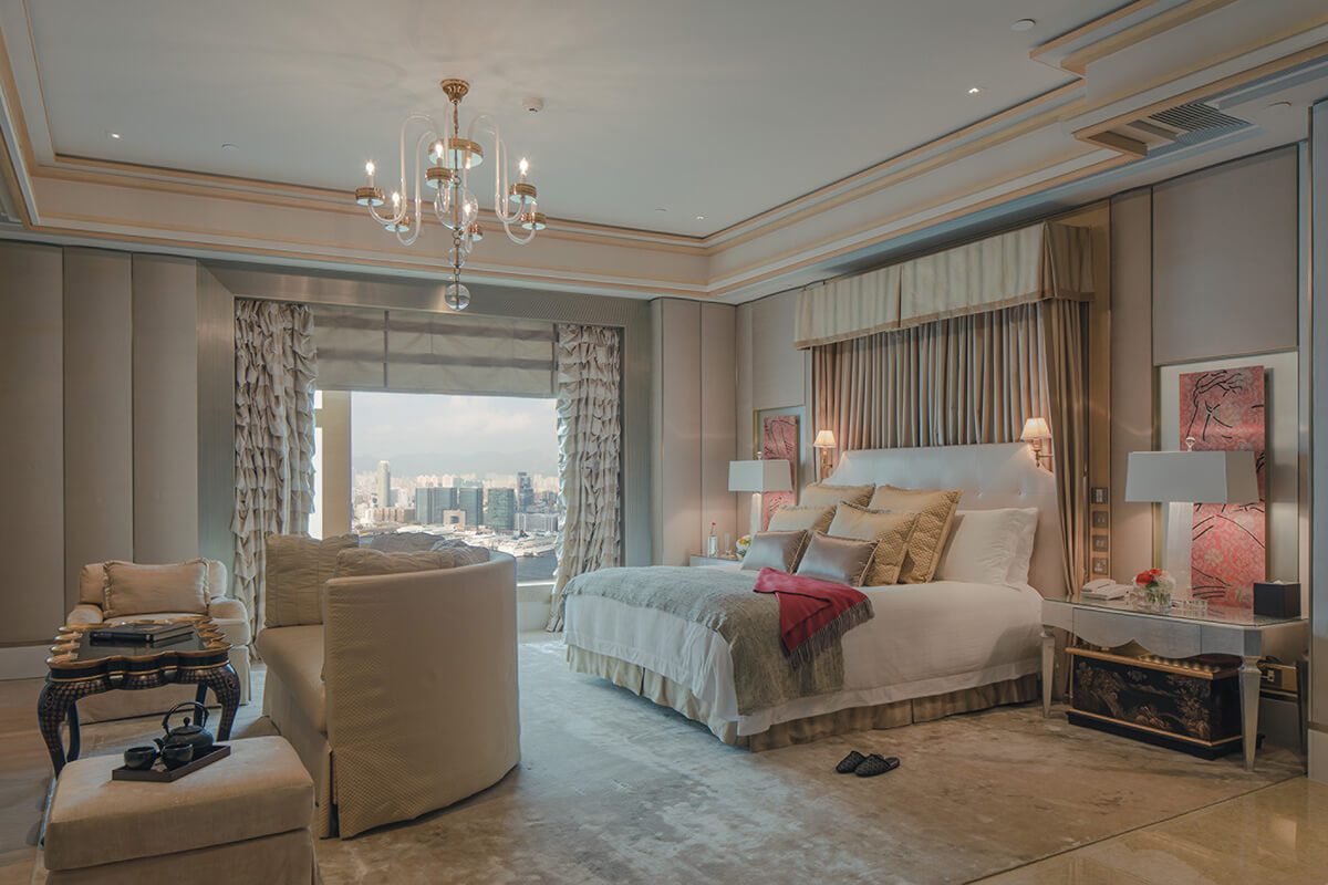 Luxury hotel suite with plush double bed, chandelier and soft, cream furnishings