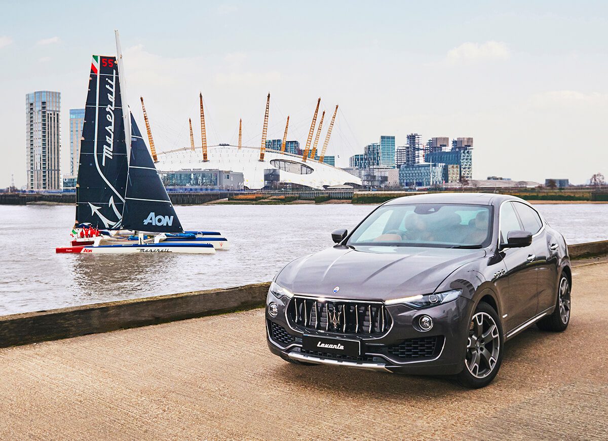 Maserati sailing boat with maserati car parked in front on the road
