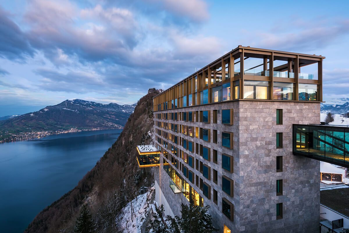 Mountainside hotel overlooking lake pictured at night with snowy surroundings