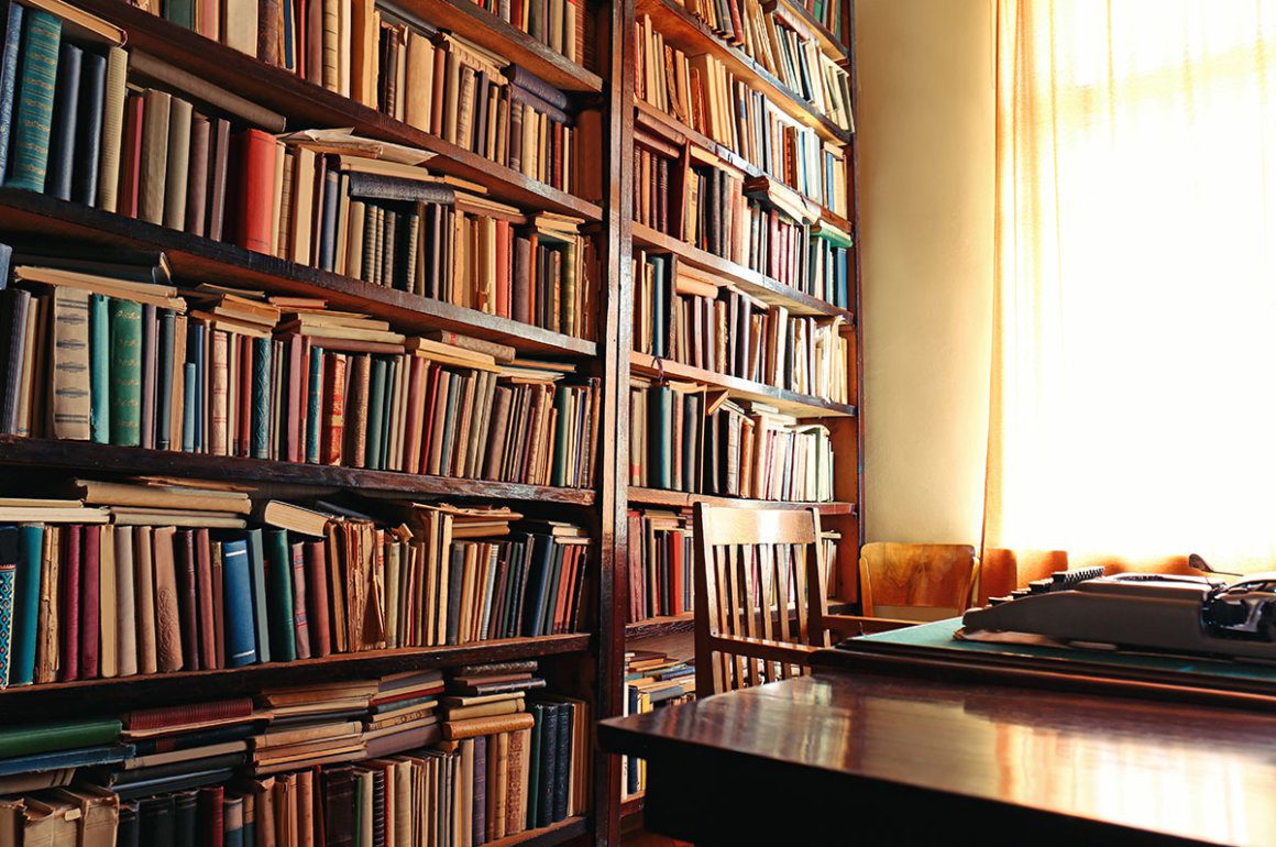 Vintage library scene with wooden bookshelves and a table and chair at the window