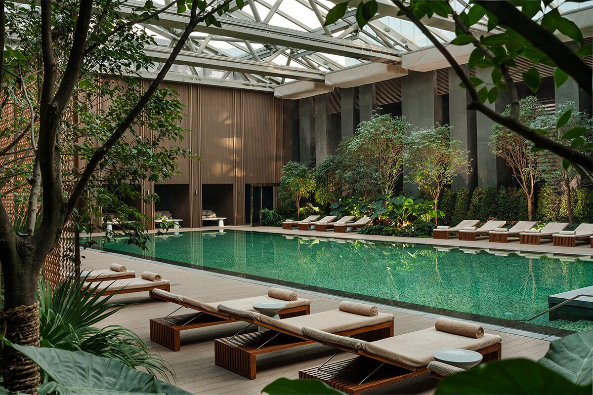 Luxury indoor swimming pool surrounded by plants inside a glass atrium