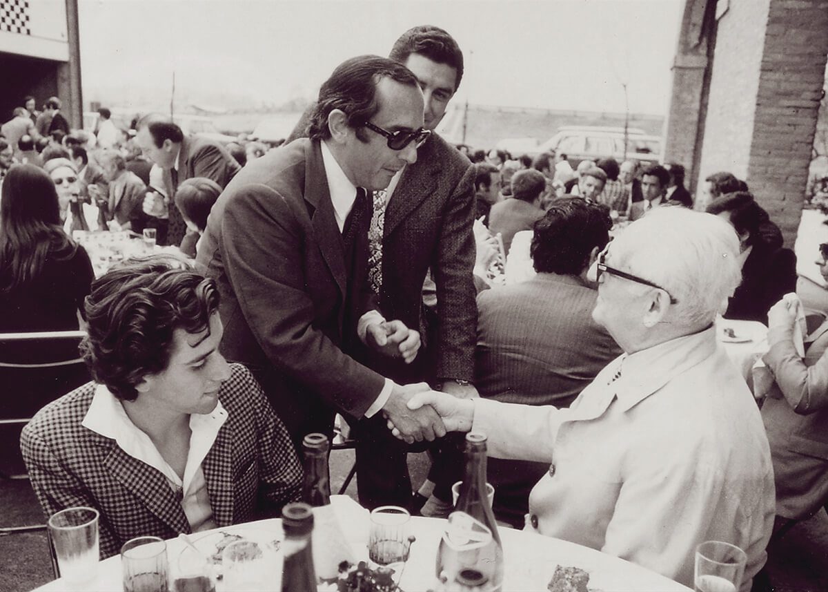 Vintage photograph of Jack Heuer of TAG Heuer swiss watches greeting Enzo Ferrari seated at a table