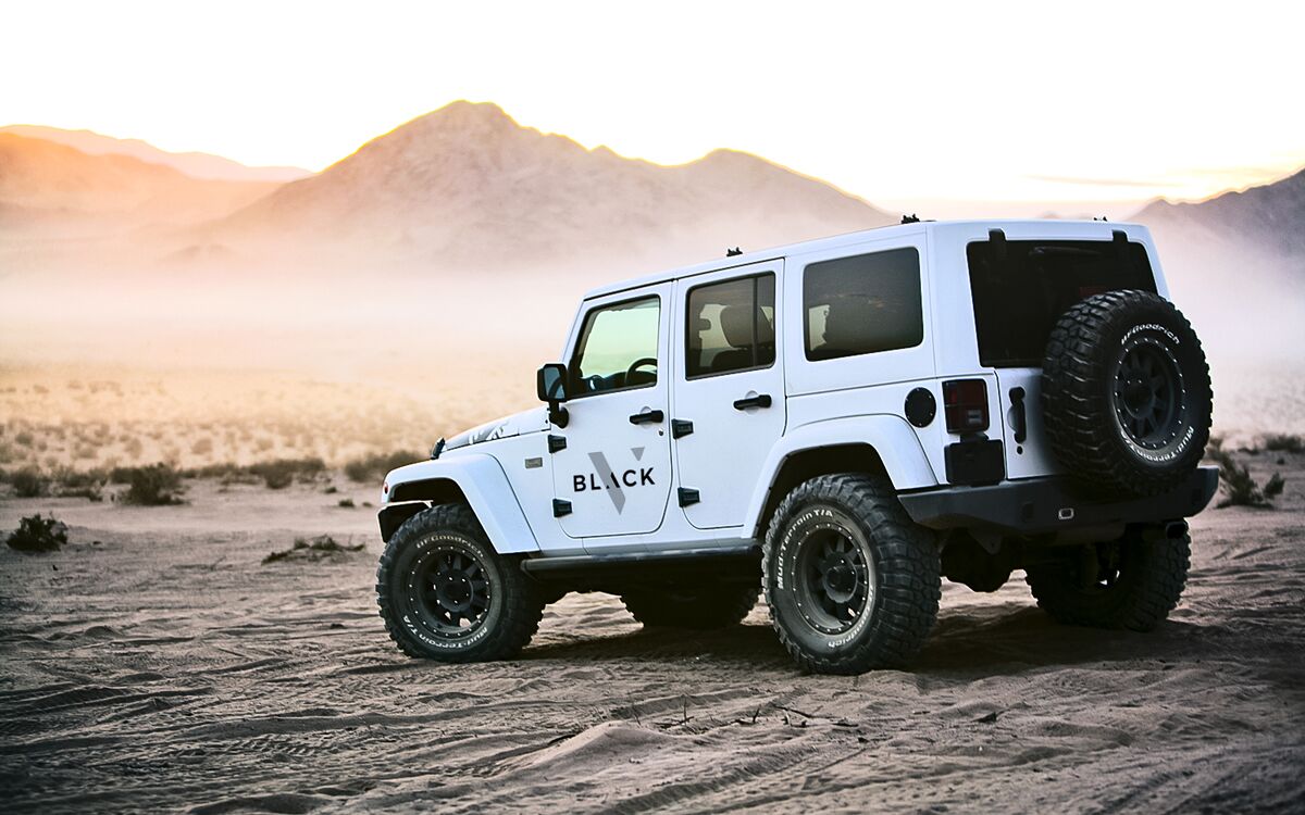 Velocity black branded truck in a desert facing sand dunes
