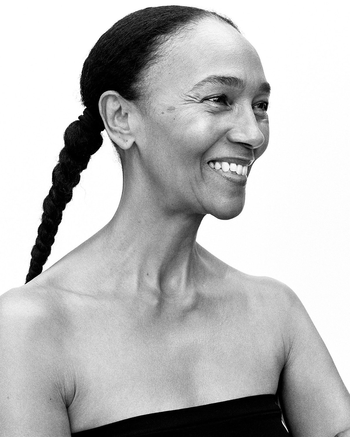 Black and white portrait of a female model with hair in plaits laughing