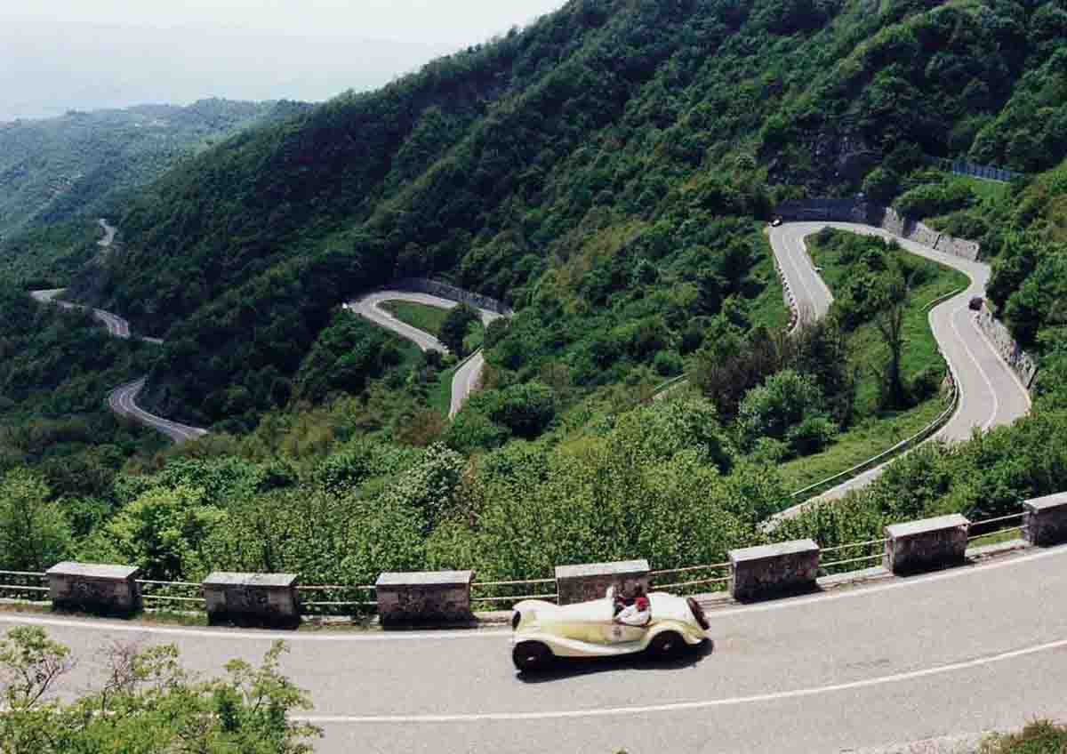 A classic car driving along a mountainous road