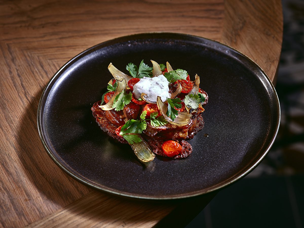 A salad arranged artistically on a black ceramic plate