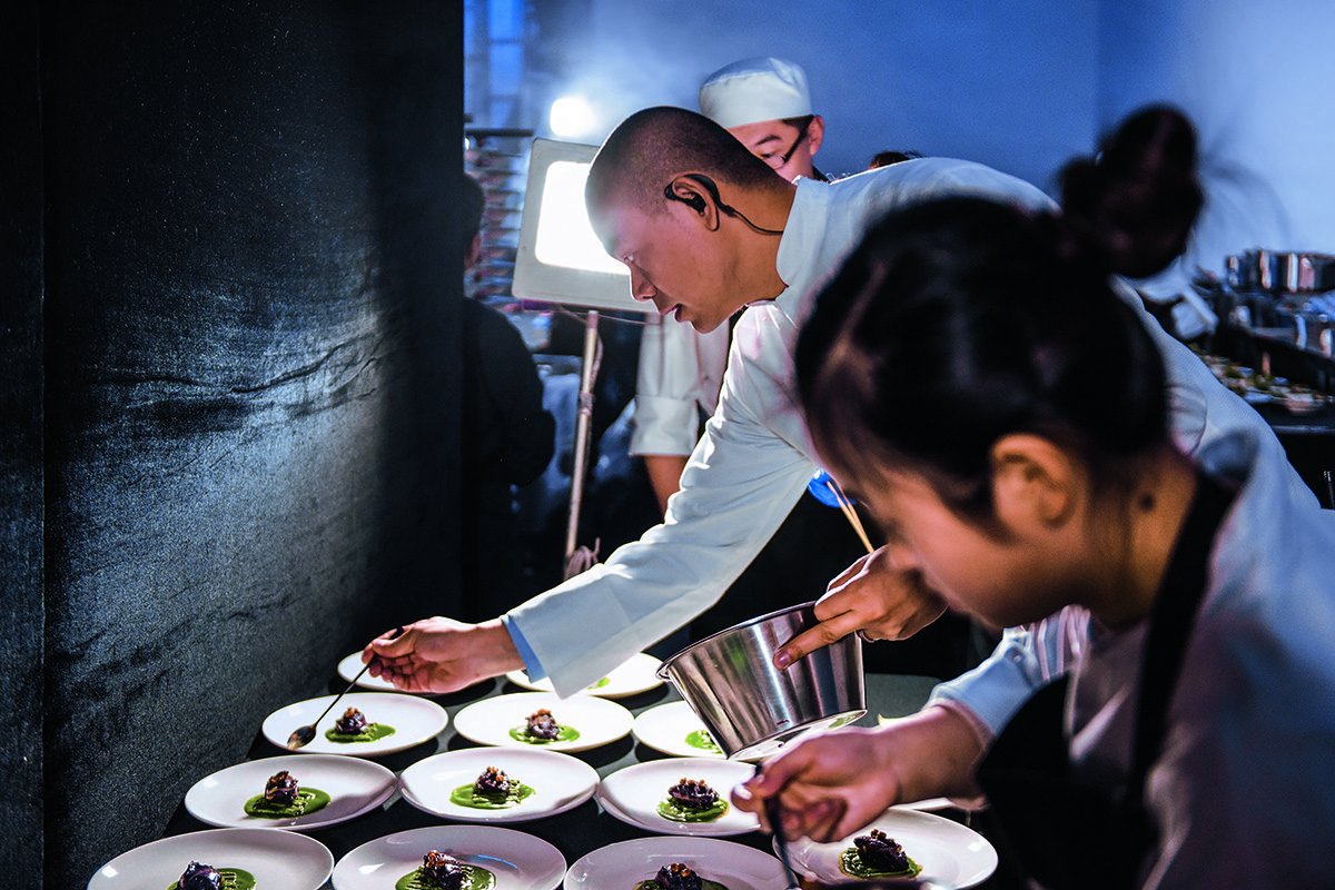 A chef and assistant plating up dinner in the kitchen