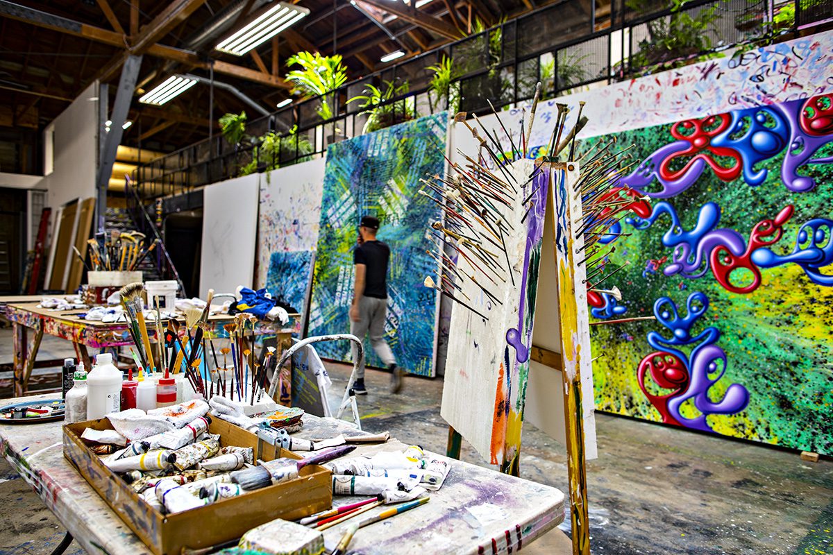 Artist studio with huge painted canvases and paint brushes