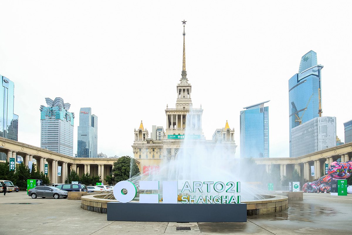 Sign for Art021 art fair in front of a water fountain and skyscrapers