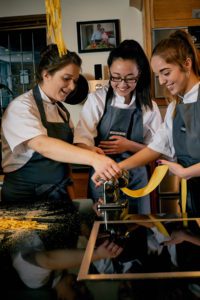 Cookery class students rolling pasta