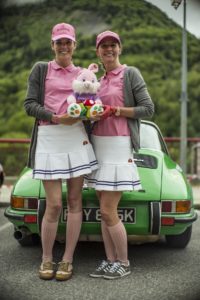 Two women dressed in matching outfits holding a rabbit teddy