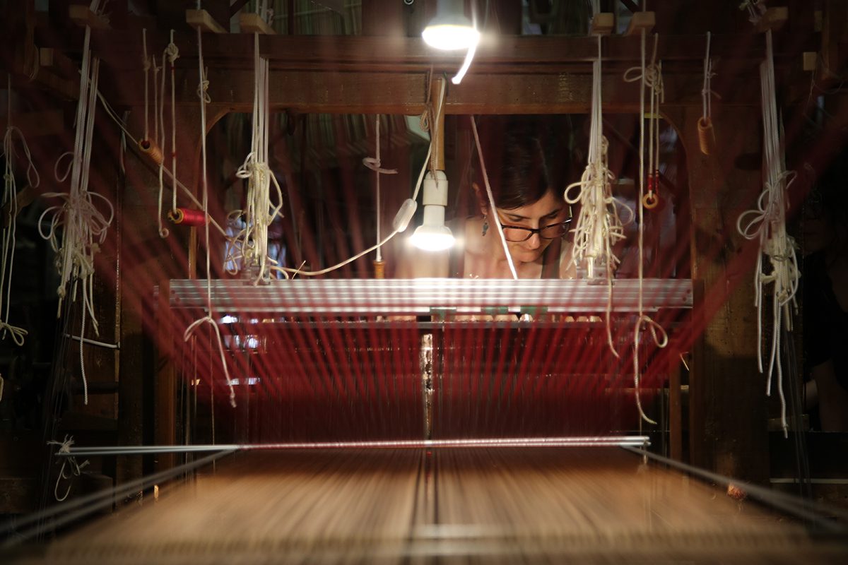 A woman using an old fashion weaving machine