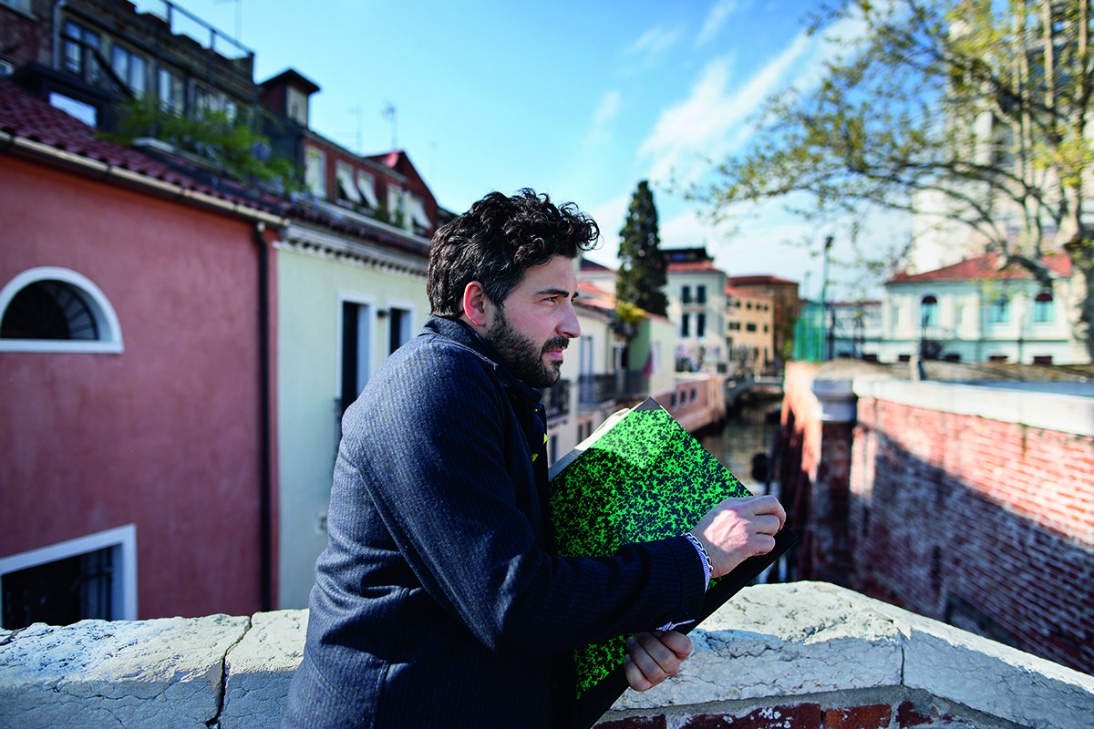 A man standing on a bridge holding a notebook
