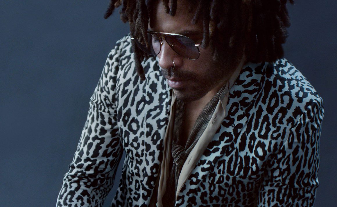 Lenny Kravitz wearing an animal print blazer holding champagne