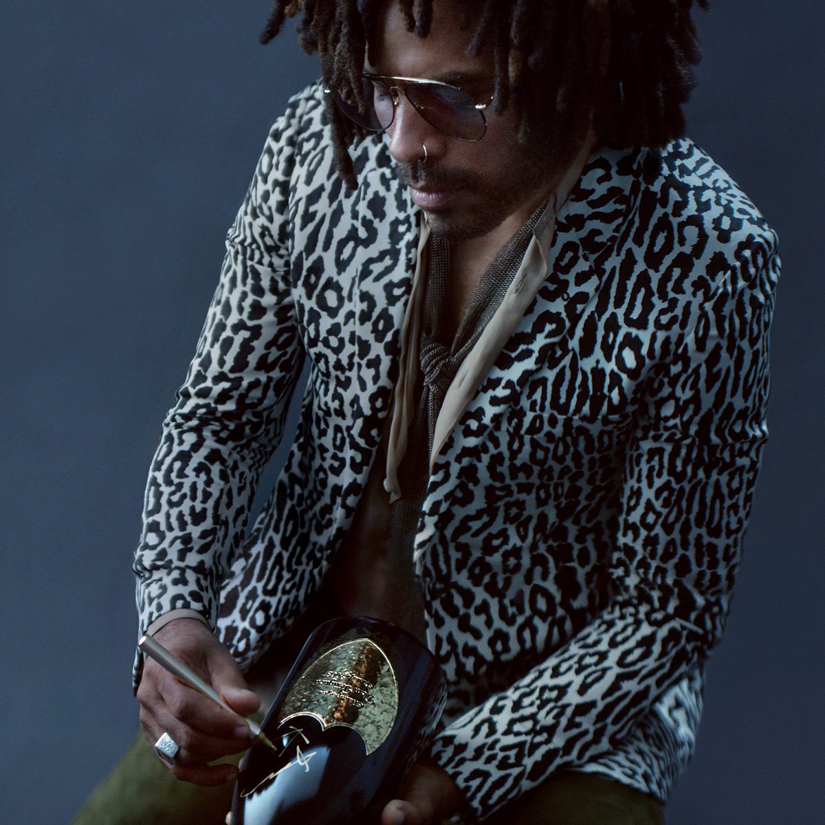 Lenny Kravitz wearing an animal print blazer holding champagne