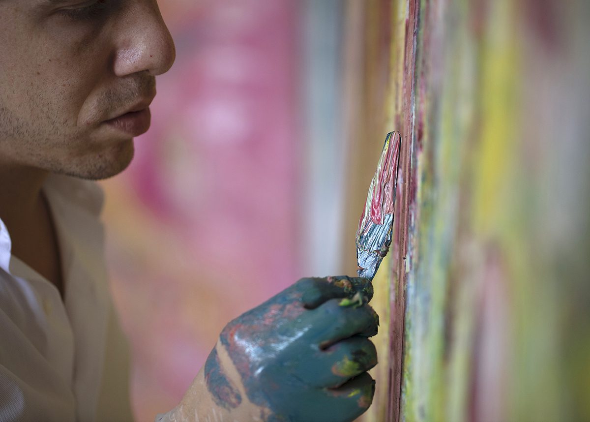 Detail painting of an artist applying paint onto a canvas
