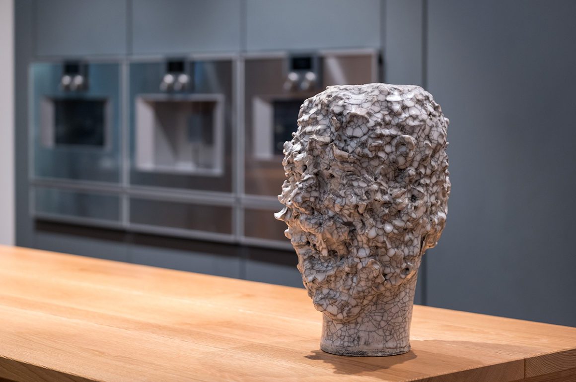 Sculpture of a head standing on a counter in a kitchen