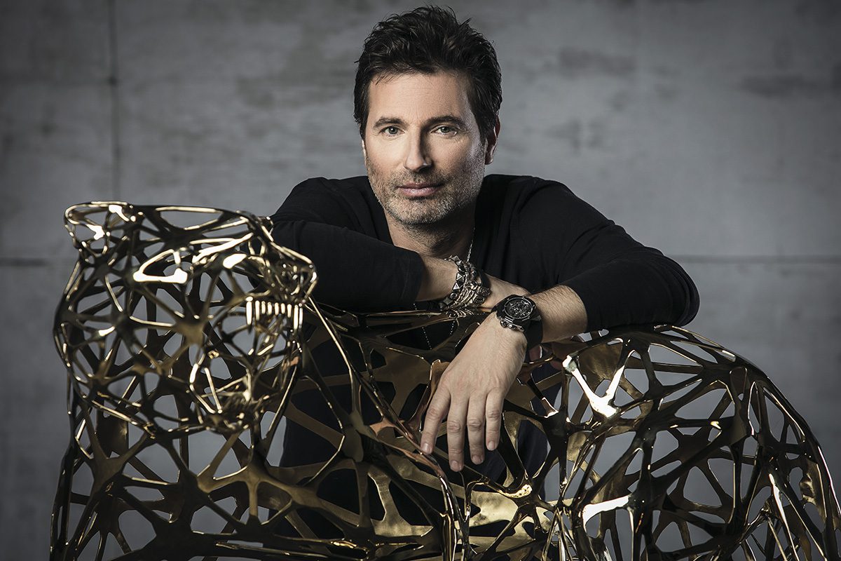 Man wearing a watch draped over a sculpture