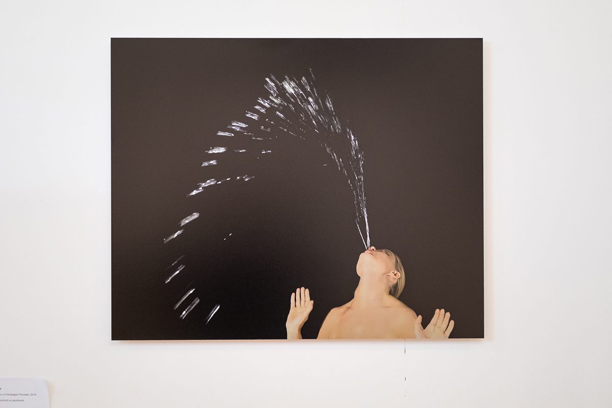Woman spitting fountain of water against black background
