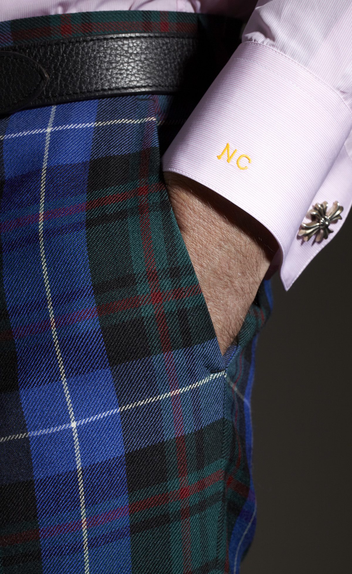 Detail image of man's hand in pocket of tartan trousers
