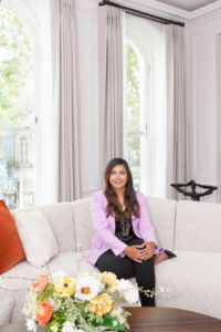 A woman sitting on a sofa with flowers on a table in front of her