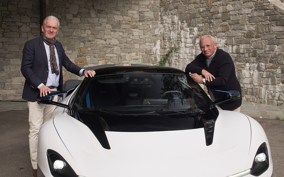 Two men standing by a white car