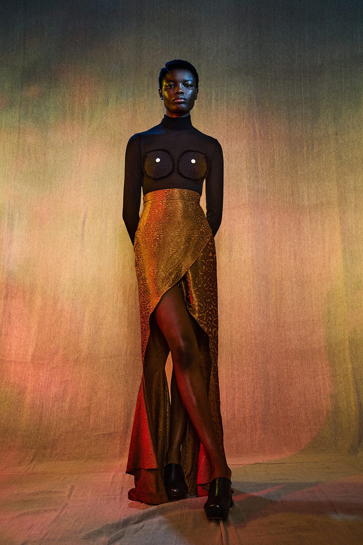A woman wearing a black top and gold sparkly skirt with a slit in it