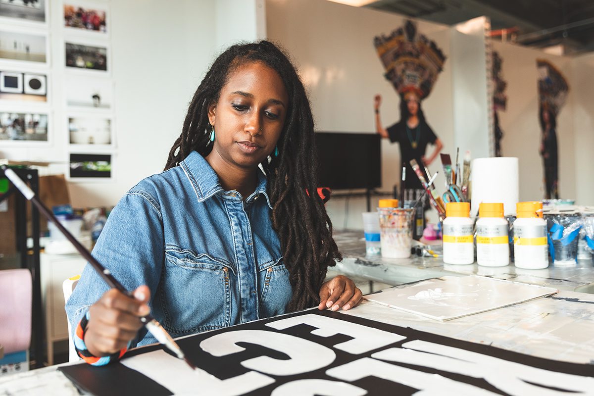 A woman painting in a denim shirt
