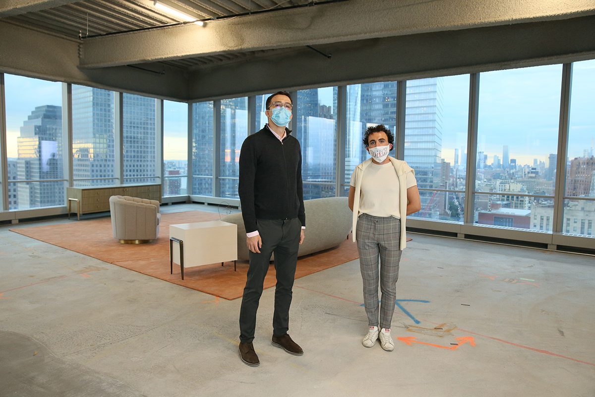 Two men standing with masks on in a lounge in a skyscraper
