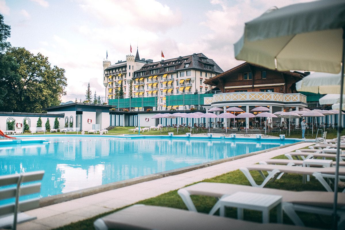 A large palace style hotel with a pool in front of it