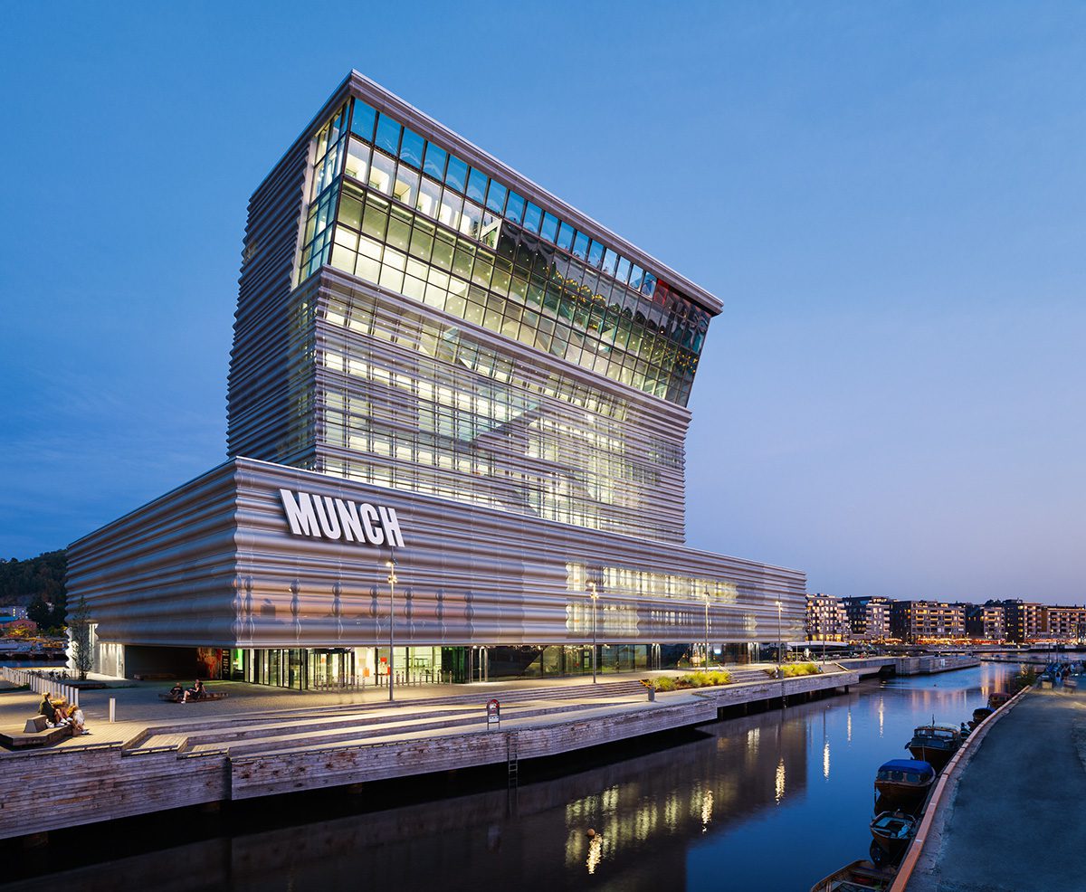 A large cement building by a river that says MUNCH on the side of it