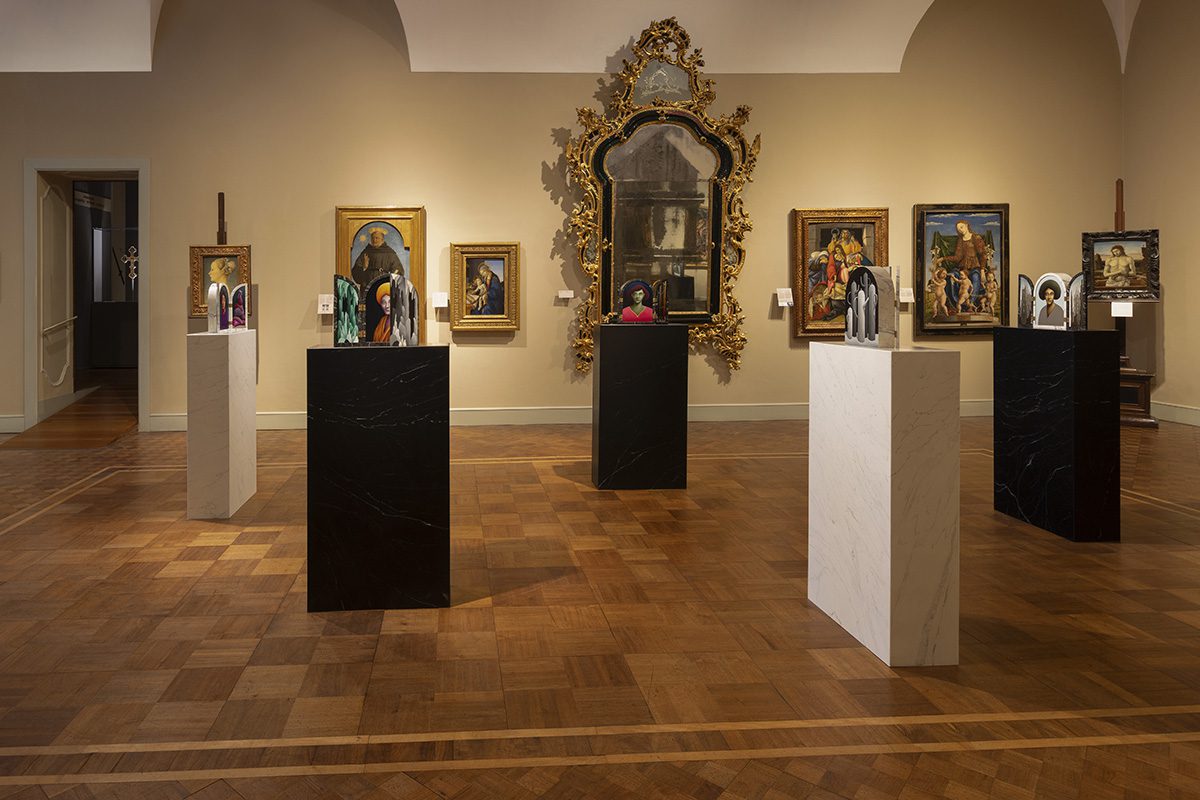 paintings on the walls and on stands in a gallery