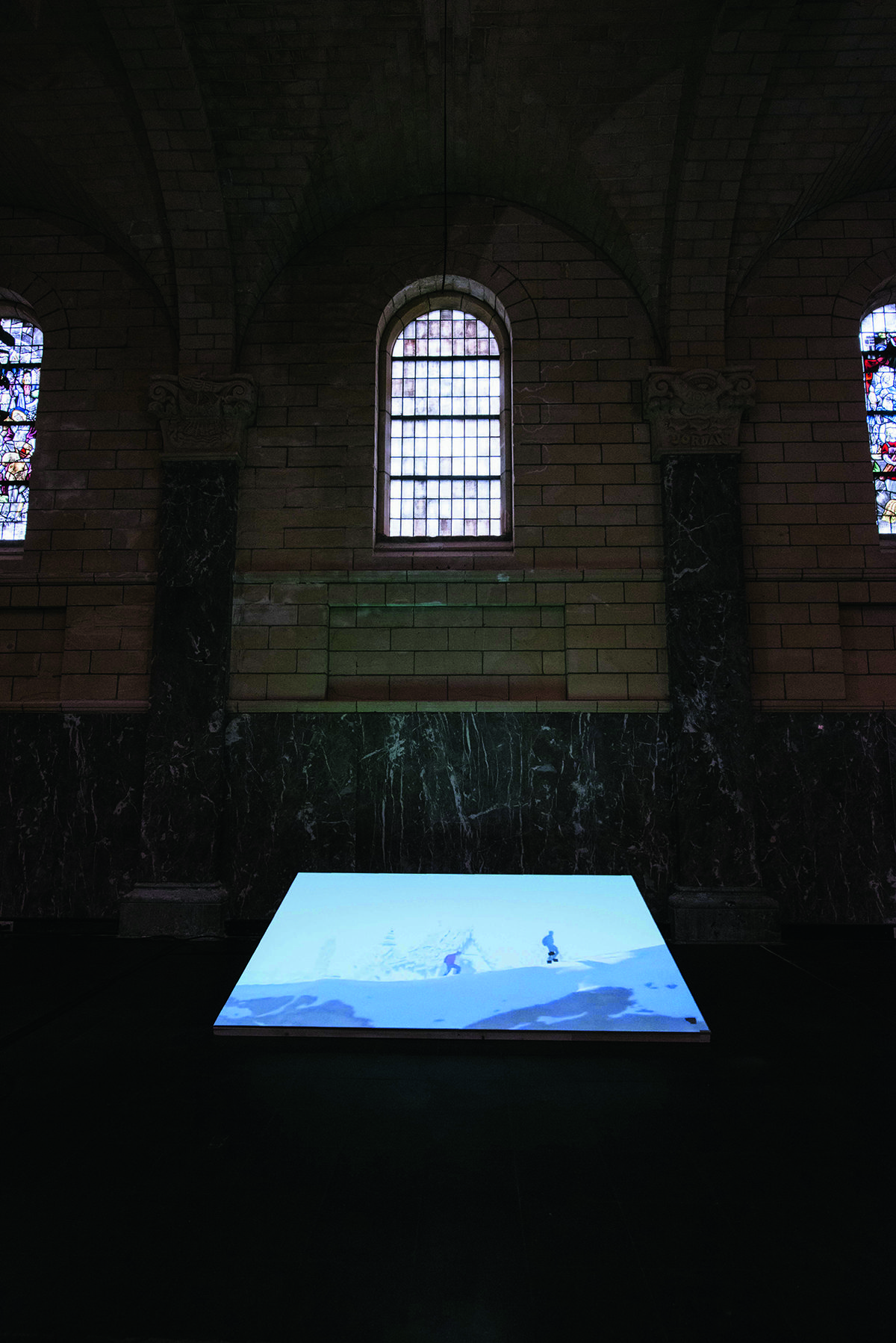 A screen with a picture on it under a stained glass arched window