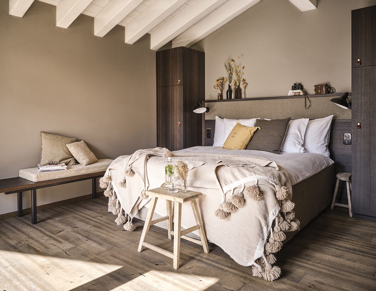 A bed with a throw and yellow and brown cushions on a white bed 