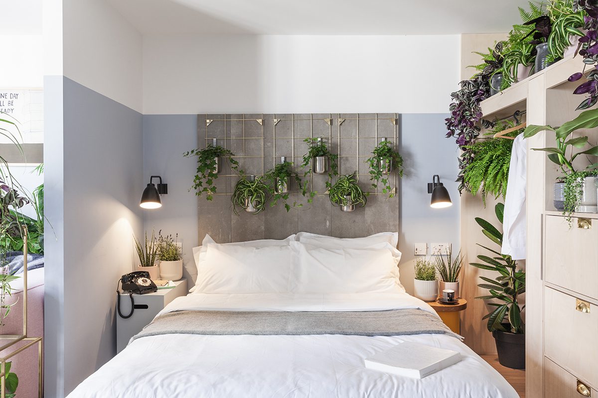 A bed with white sheets and plants around it 