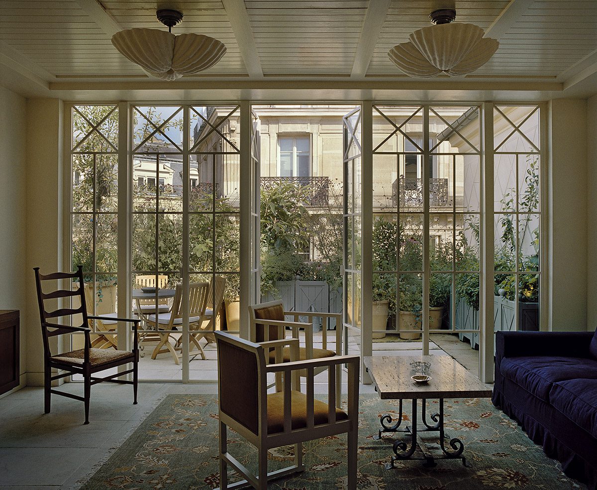 A lounge with a floor to ceiling glass doors and a terrace with plants