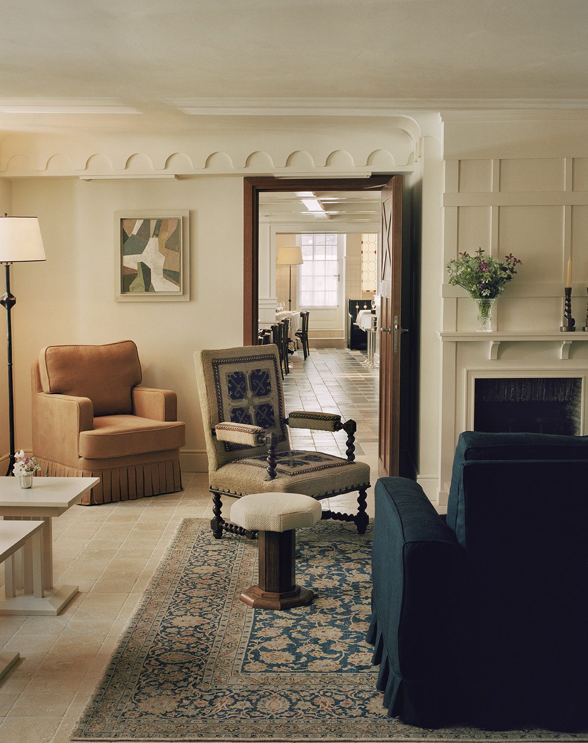 a lounge with an orange velvet chair, a blue velvet chair and a cream wooden chair