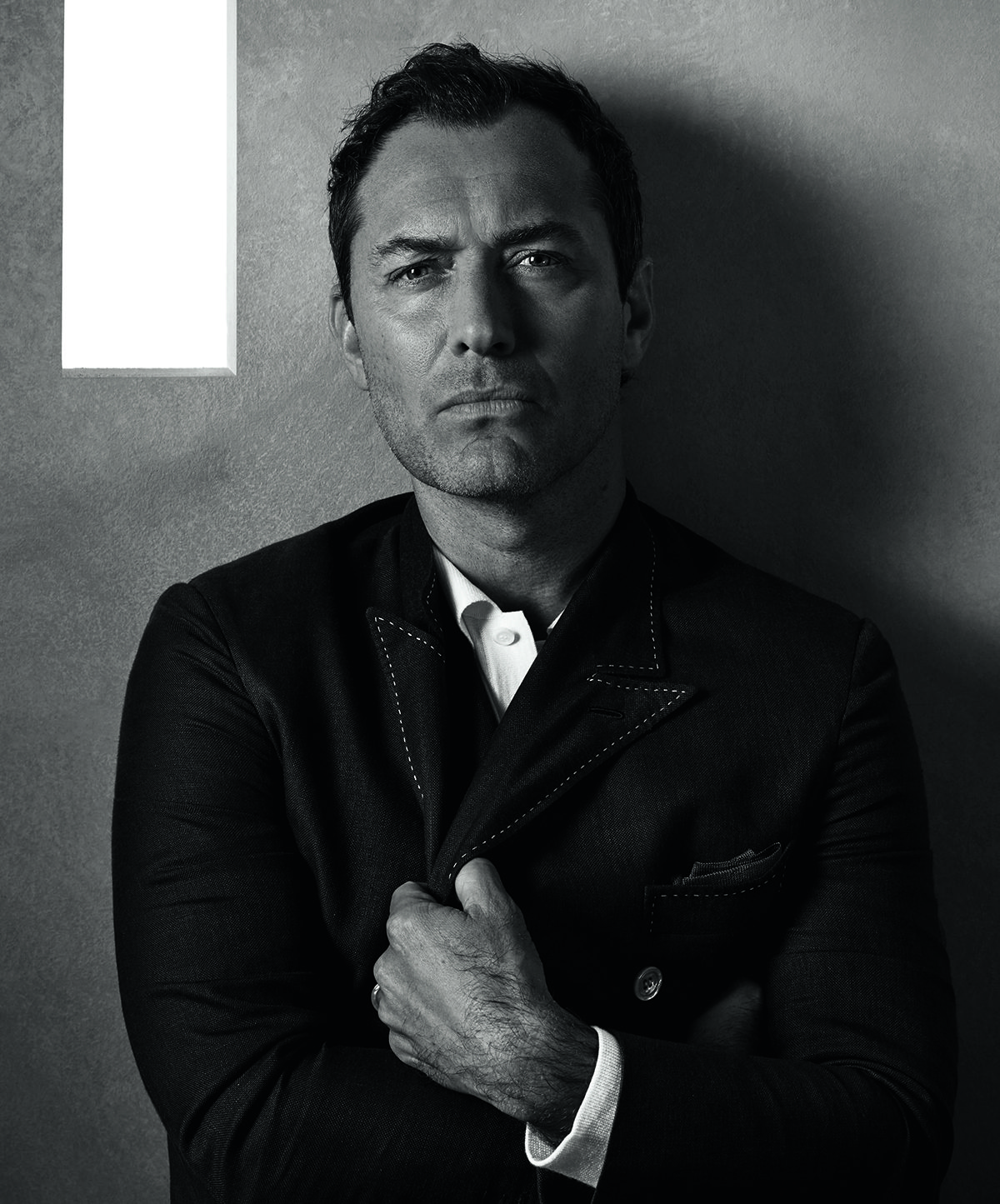Jude Law holding his jacket over his shirt