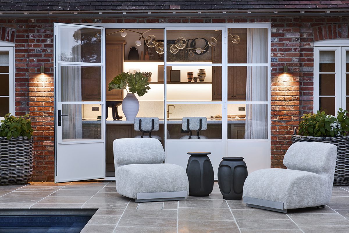 FBC London Outdoor Collection (1) white chairs by a pool with a dining room in the background