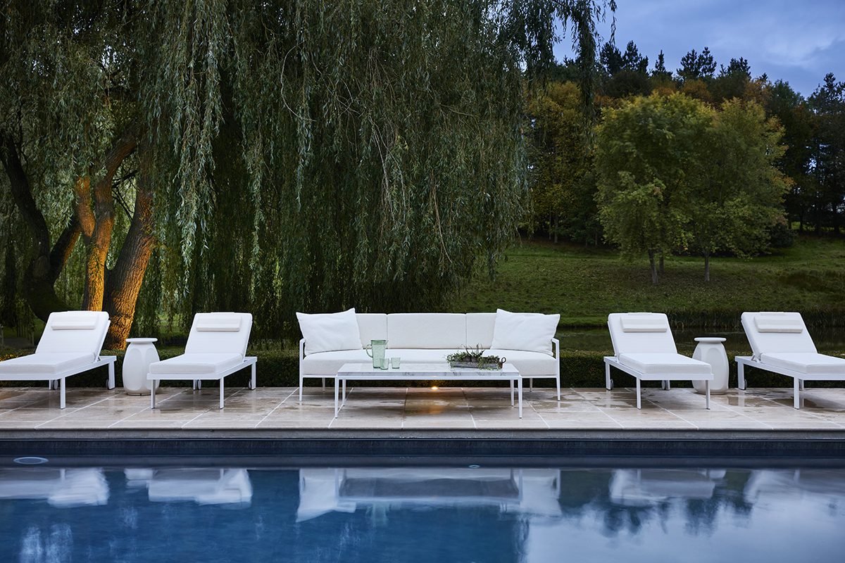 FBC London Outdoor Collection (2) white lounge chairs by a swimming pool under a willow tree