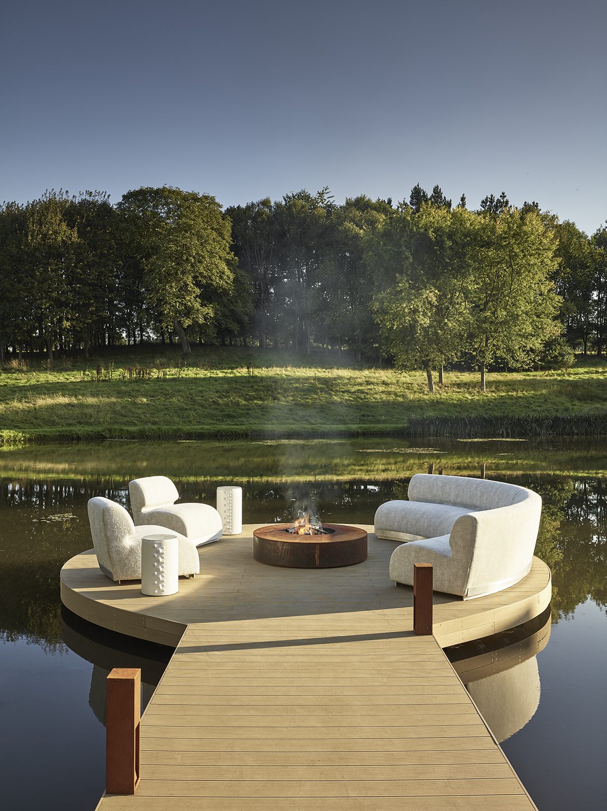 HyperFocal: 0 a deck on a lake with a fire and sofas in a circle at the end
