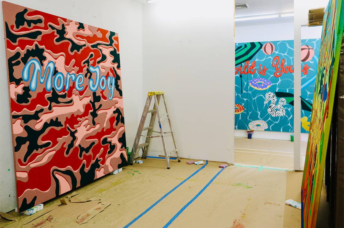 a red painting in a gallery that says More Joy in blue writing