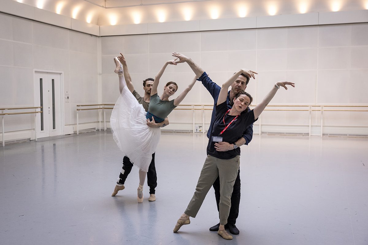 Ballerinas training in a studio and one is wearing a white tutu