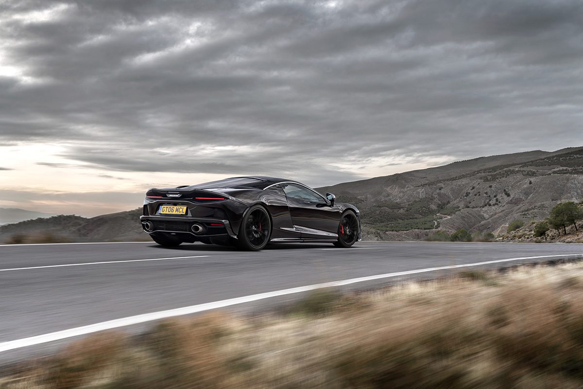 A black car driving on a road with mountains in the distance