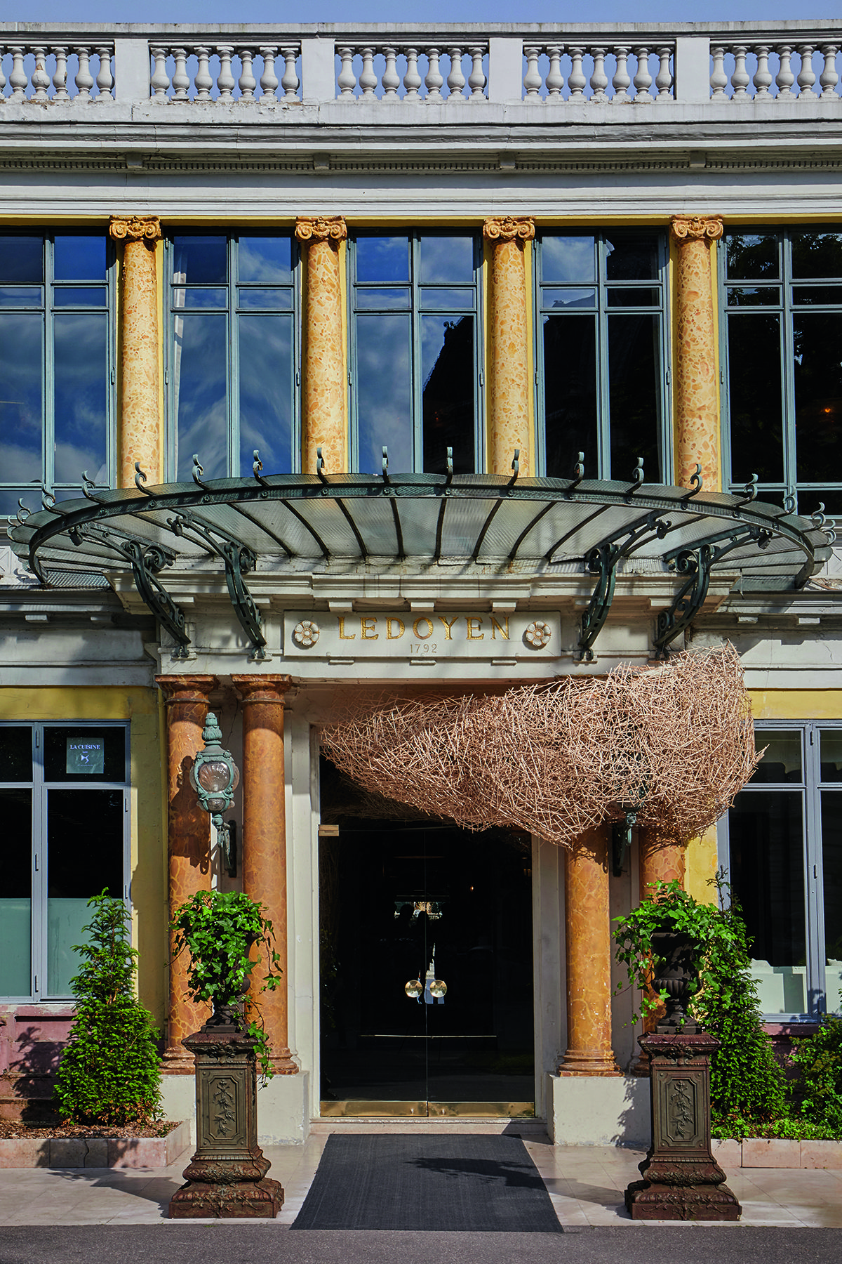 The entrance of a grand home with yellow walls and an artwork coming out the house