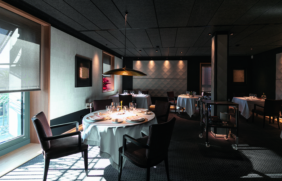 A restaurant with a large grey light hanging over the table