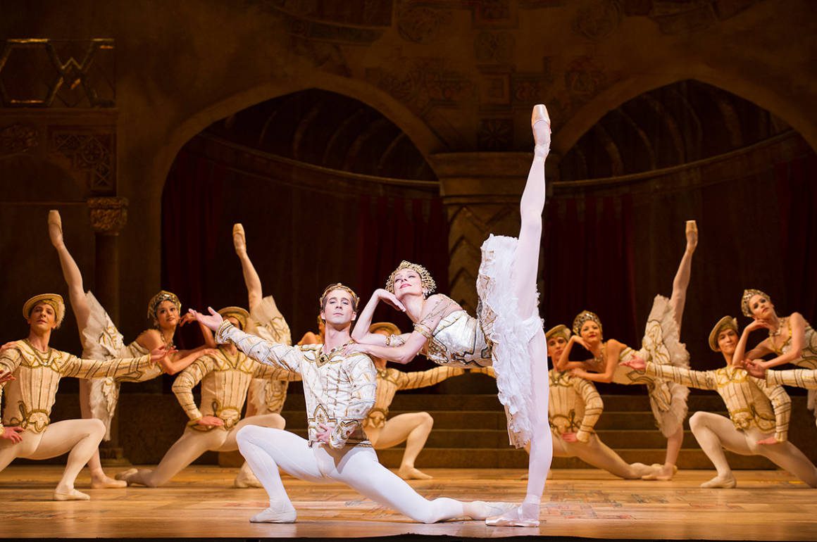 A ballet performance with people dressed in white and gold