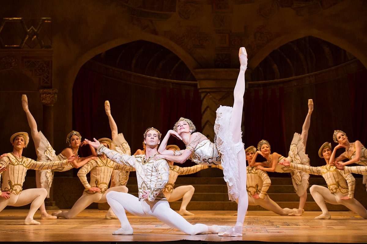 A ballet performance with people dressed in white and gold