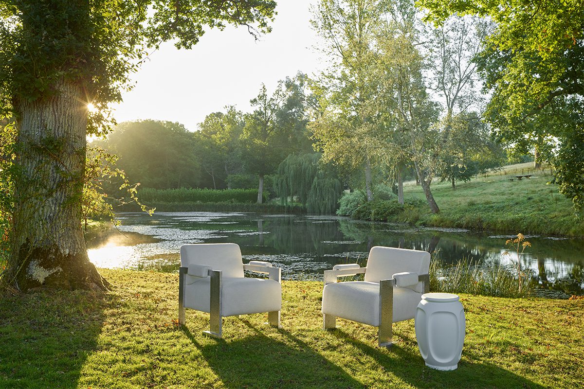 feature white chairs on the grass by a pond